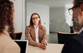 Jeune femme en entrevue d’embauche, assise face à deux recruteurs